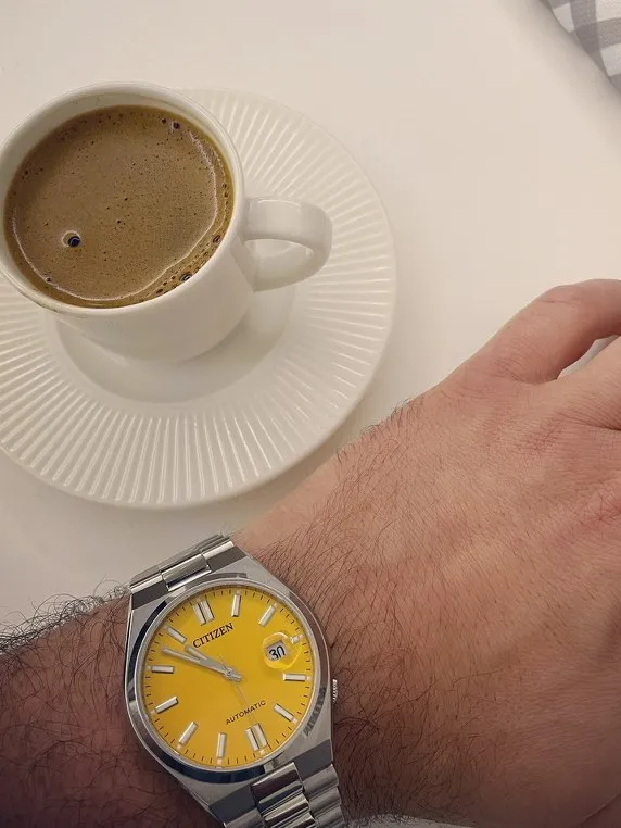 Beyaz masada kahve eşliğinde sarı kadranlı Citizen Tsuyosa
